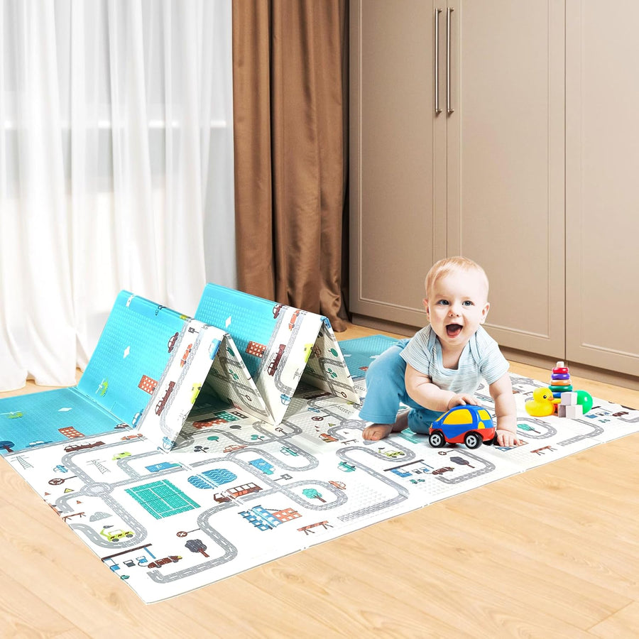 A colorful play mat featuring a town scene with roads, buildings, and parks, laid out on a wooden floor. A toddler plays with toy cars on the mat, surrounded by soft, folded play mats in the background.